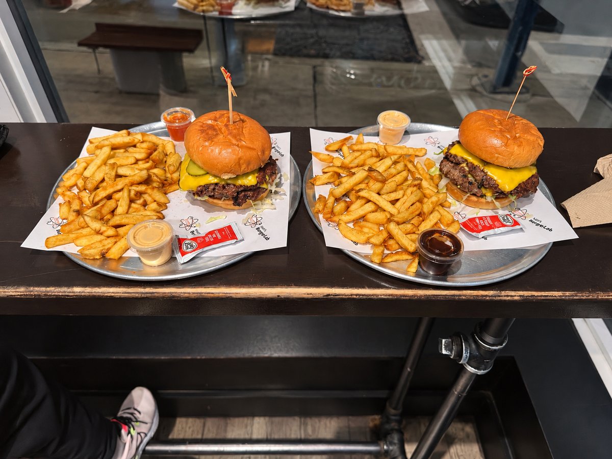 Two double smash burgers with fries and dipping sauces at Matt's Burger Lab, Queen Street West, Toronto