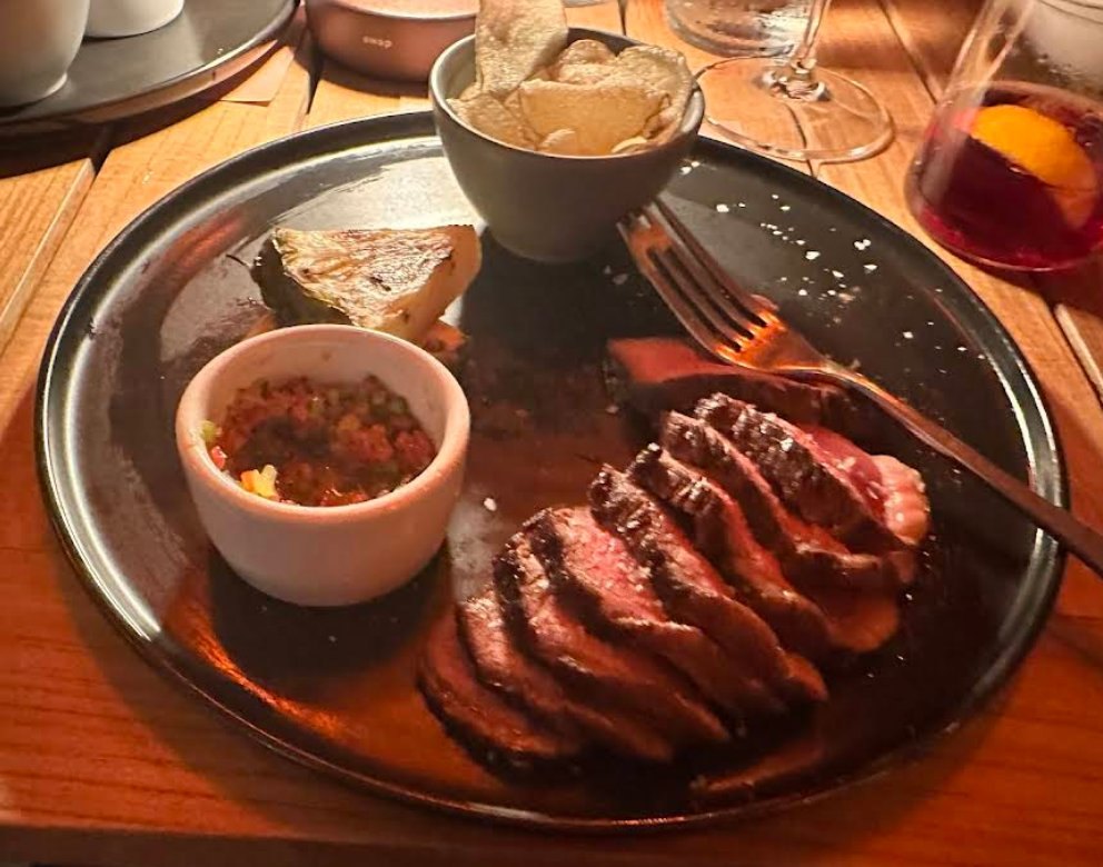 Sliced picanha steak with potatoes and chimichurri at Pom Pom